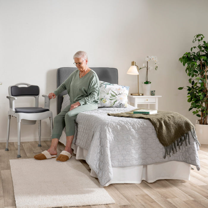 Caregiver helping elder to use potty chair